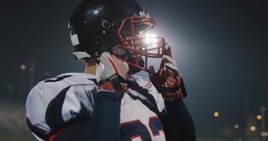 Amerikaans Amerikaans voetbal speler zetten Aan helm Aan groot stadion met lichten in achtergrond foto