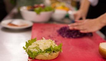 chef snijdend salade voor hamburger foto