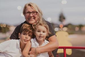 een ouder grootmoeder is spelen met haar kleinkinderen in een park Bij zonsondergang. selectief focus foto