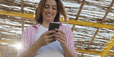 smartphone vrouw sms'en Aan cel telefoon Bij strand foto