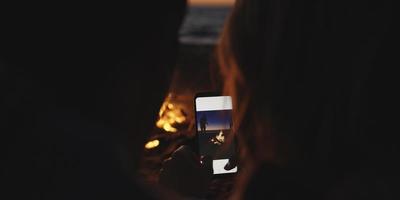 paar nemen foto's naast kampvuur Aan strand foto