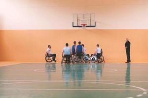 gehandicapt oorlog veteranen gemengd ras tegengesteld basketbal teams in rolstoelen gefotografeerd in actie terwijl spelen een belangrijk bij elkaar passen in een modern hal. foto