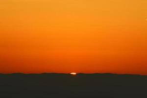 zonsopkomst Aan de kust van de dood zee in Israël. de zon stijgt van achter de bergen in Jordanië. foto