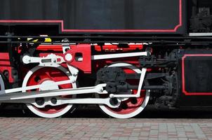 wielen van de oud zwart stoom- locomotief van Sovjet keer. de kant van de locomotief met elementen van de roterend technologie van oud treinen foto