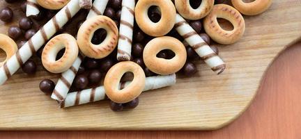 krokant buisjes, chocola smelten ballen en bagels liggen Aan een houten oppervlak. mengen van divers snoepgoed foto