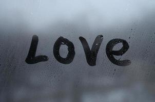 de Engels woord liefde is geschreven met een vinger Aan de oppervlakte van de beneveld glas. Verenigde staten van Amerika foto