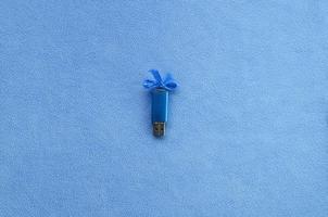briljant blauw USB flash geheugen kaart met een blauw boog leugens Aan een deken van zacht en harig licht blauw fleece kleding stof. klassiek vrouw geschenk ontwerp voor een geheugen kaart foto