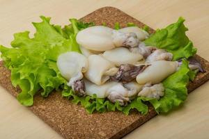 rauw inktvis Aan houten bord en houten achtergrond foto