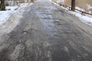 beschadigd asfalt weg met kuilen veroorzaakt door bevriezing en ontdooien cycli gedurende de winter. arm weg foto