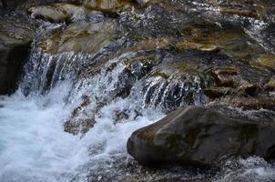 detailopname beeld van een klein wild waterval in de het formulier van kort streams van water tussen berg stenen foto