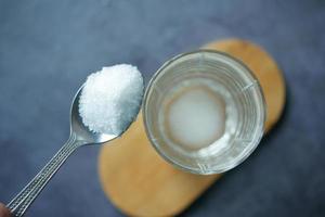 witte suiker in een glas water op tafel gieten foto