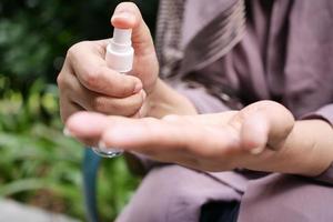 jong Dames hand- gebruik makend van hand- ontsmettingsmiddel verstuiven buitenshuis foto