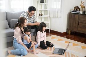 Aziatisch familie met kinderen gebruik makend van laptop computer Bij huis foto