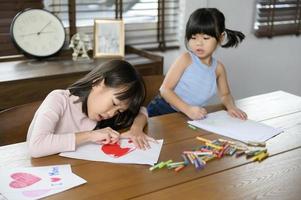 Aziatisch kinderen tekening en schilderij Aan tafel in spelen kamer Bij huis, leerzaam spel. foto