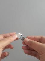 een hand- is proberen naar insert een klein fles schijf in een adapter USB type c naar USB 3.0 type-c adapter otg foto