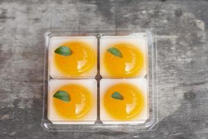 Thais oranje gelei in plastic doos Aan oud houten tafel. foto