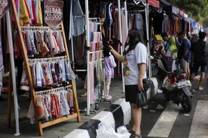 magelang, indonesië.05 10 2022. een vrouw is kiezen kleren Bij een verkoper's stand Bij een auto vrij dag evenement. foto