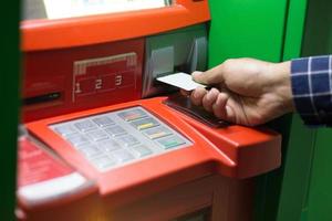 hand- invoegen Geldautomaat kaart in bank machine naar terugtrekken geld. foto