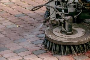 de gemeentelijk onderhoud voert seizoensgebonden werk in de park. de veger picks omhoog een veel van brokstukken. de borstels vegen de asfalt foto