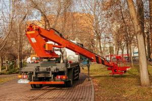 dnepropetrovsk, Oekraïne - 11.22.2021 een mobiel kraan met een oranje kleur mand is gebruikt in een openbaar park naar trimmen bomen. foto