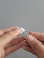 een hand- is proberen naar insert een klein fles schijf in een adapter USB type c naar USB 3.0 type-c adapter otg foto