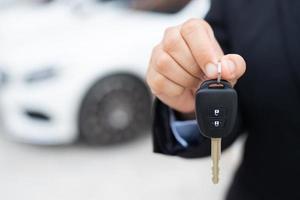 verkoper is draag- de auto sleutels geleverd naar de klant Bij de toonzaal met een laag interesseren bieden. speciaal Promotie foto