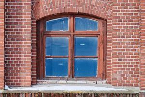 een gebogen glazen raam op oude rode bakstenen muur foto