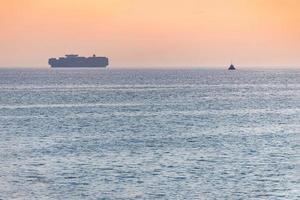 kleine sleepboot en groot vrachtschip. prachtige zonsondergang over zee. adembenemende reisweergave, kopieer ruimte. foto