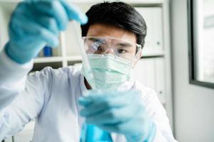 mannetje wetenschapper werken in een laboratorium met blauw test buizen. Aziatisch mannetje wetenschapper onderzoeker in de laboratorium medisch technologie en drug Onderzoek en ontwikkeling concepten. foto