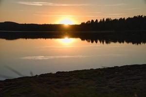 zonsondergang met reflectie Aan een Zweeds meer in klein en. romantisch avond humeur foto