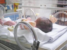 pasgeboren baby meisje binnen incubator in ziekenhuis post levering kamer foto