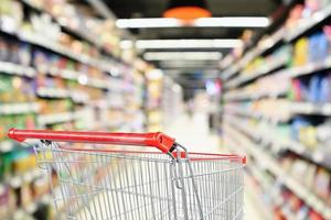 supermarkt gangpad wazig achtergrond met lege rode winkelwagen foto