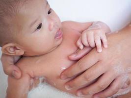 Aziatisch pasgeboren baby meisje het baden met moeder foto