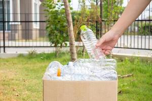 hand- houden en zetten plastic flessen in naar bruin recycle vuilnis doos foto
