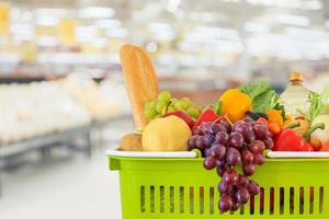 winkelmandje gevuld met groenten en fruit met supermarkt supermarkt wazig onscherpe achtergrond met bokeh licht foto