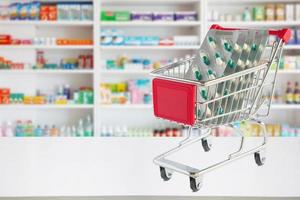 geneeskunde pillen capsule in winkelwagen op apotheek winkel teller met onscherpte drogisterij planken intreepupil achtergrond foto