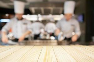 lege houten tafelblad met chef-kok koken in restaurant keuken wazig intreepupil achtergrond foto