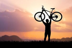 Mens houdt een fiets Aan top van een berg. concept van succes en zege foto