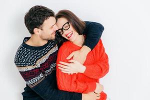 foto van aantrekkelijke jonge brunette vrouw geniet van vrije tijd met haar vriendje, heeft een vrolijke uitdrukking, sluit de ogen en glimlacht gelukkig, geïsoleerd op een witte achtergrond. mensen en liefde concept