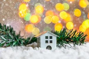 abstract komst Kerstmis achtergrond. speelgoed- model- huis en winter Spar Afdeling Aan achtergrond met sneeuw en onscherp slinger lichten. Kerstmis met familie Bij huis concept. foto