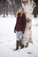 vrouw leunend tegen boom in winter foto