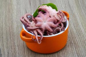 gemarineerde octopus in een kom op houten achtergrond foto