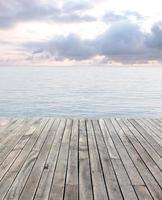 houten verdieping en blauw zee met golven en bewolkt lucht foto