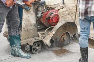 arbeider gebruik makend van diamant zag blad machine snijdend beton weg Bij bouw plaats foto