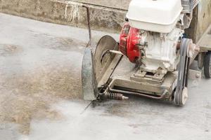 arbeider gebruik makend van diamant zag blad machine snijdend beton weg Bij bouw plaats foto