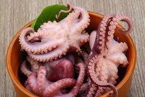 gemarineerde octopus in een kom op houten achtergrond foto