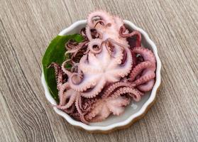 gemarineerde octopus in een kom op houten achtergrond foto