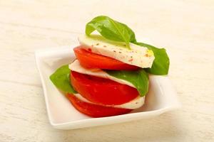 caprese salade in een kom Aan houten achtergrond foto