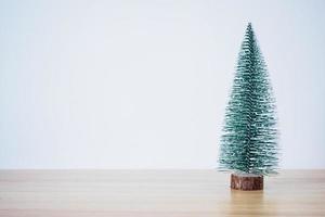 Kerstmis boom Aan hout tafel met wit muur achtergrond foto