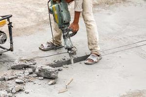 bouw arbeider gebruik makend van drilboor boren beton oppervlakte foto